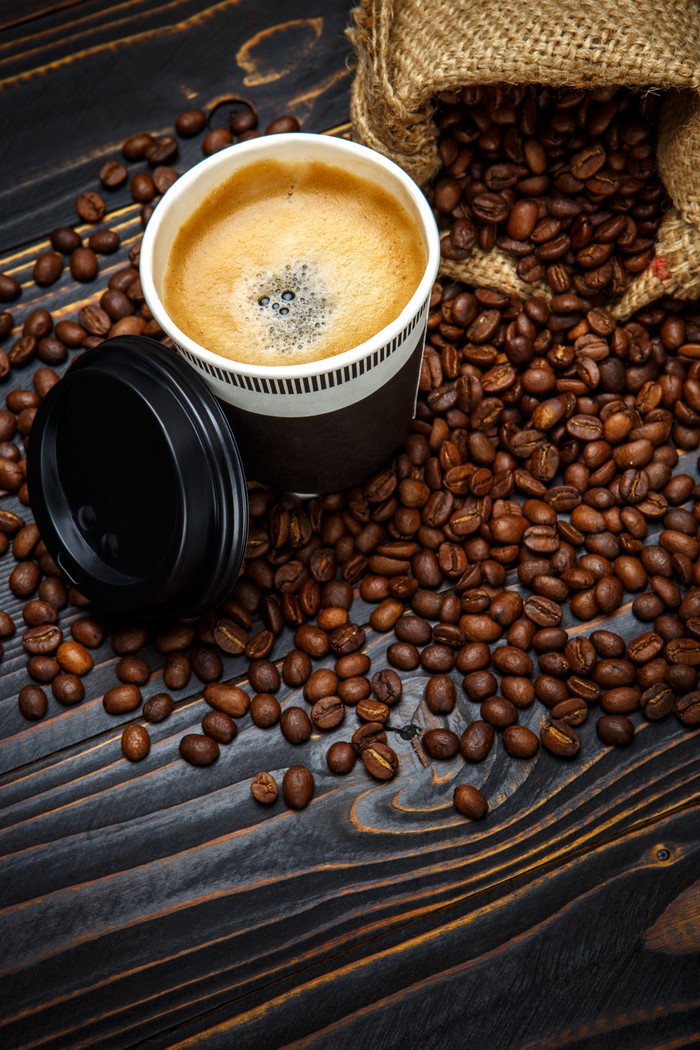 Coffee cup with coffee beans on wooden table