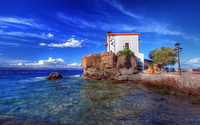 White building on a rocky cliff by the sea