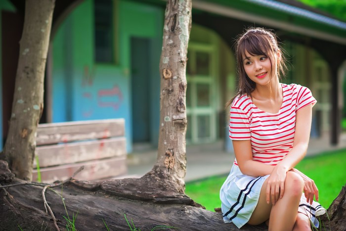 Young Woman Sitting Outdoors in Striped T-shirt