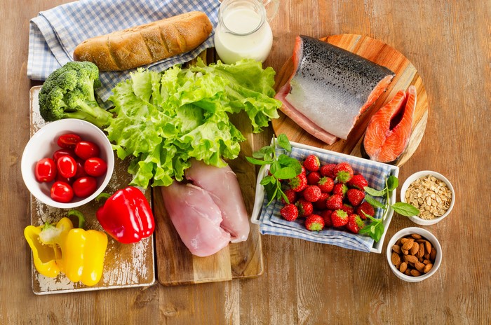 Assortment of Healthy Foods: Salmon, Chicken, Vegetables, Fruits, Bread, Nuts, and Oats