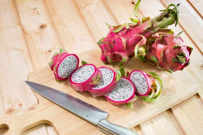 Dragon fruit on a cutting board with a knife