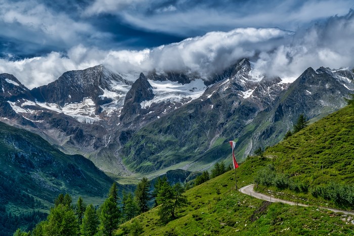 Swiss Alps mountains with clouds and a winding path