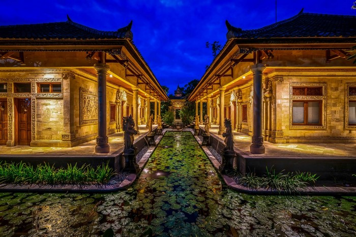 Balinese courtyard with lily pond and sculptures at night