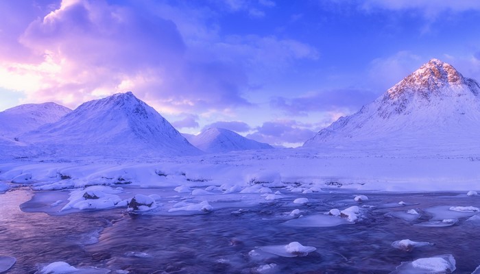 Snowy mountains and stream in Glen Coe, Scotland during winter