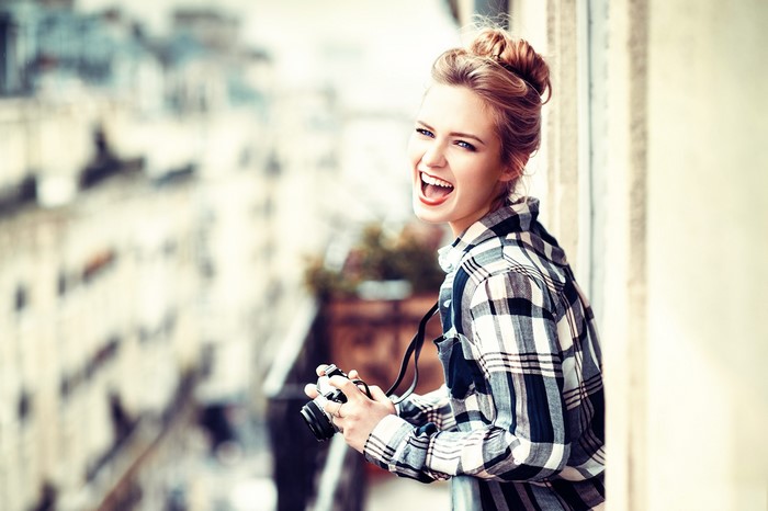 Woman with camera laughing on a balcony