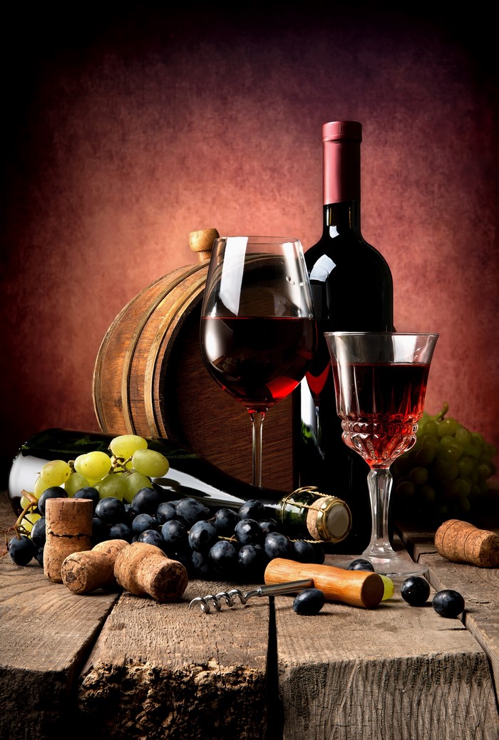 Wine bottle, glasses, grapes, and barrel on wood
