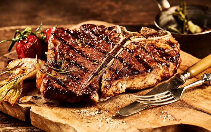 Grilled T-bone steak with tomatoes and garlic on a cutting board