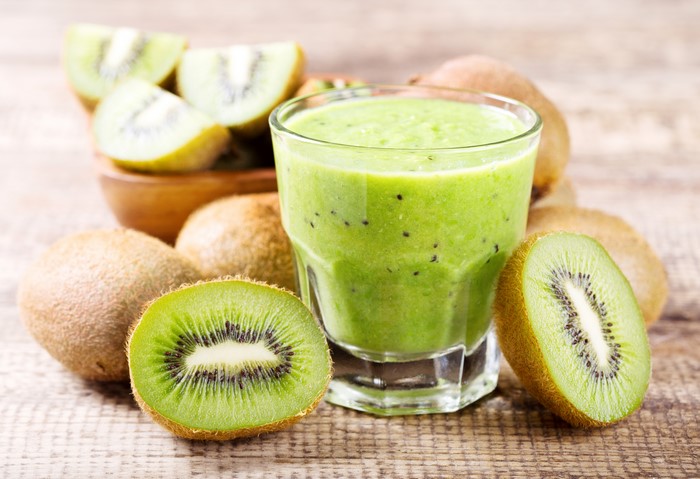 Kiwi juice in a highball glass with kiwis