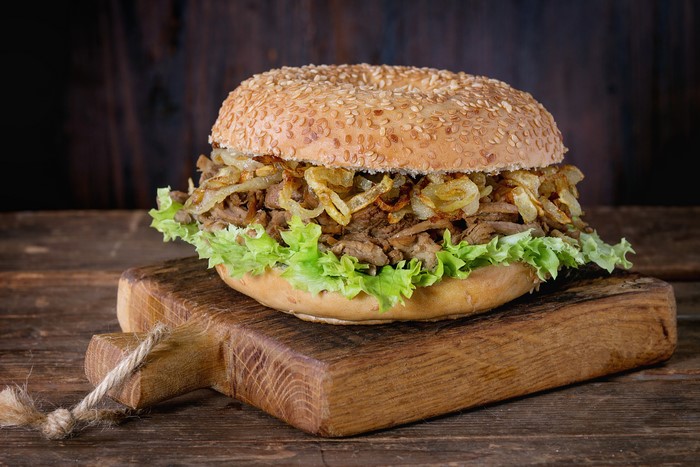 Hamburger with lettuce and fried onions on a cutting board