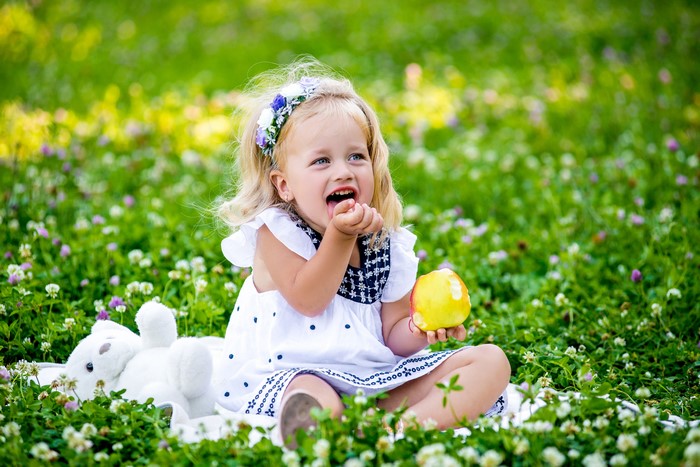 Little girl with apple in grass