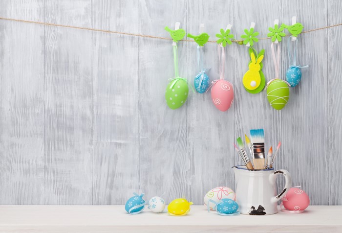 Easter eggs and paintbrushes on a wooden wall