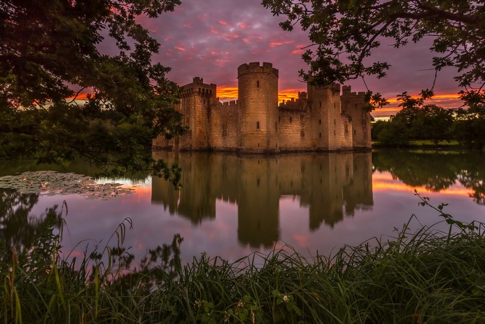 Bodiam Castle reflected in a pond at sunset