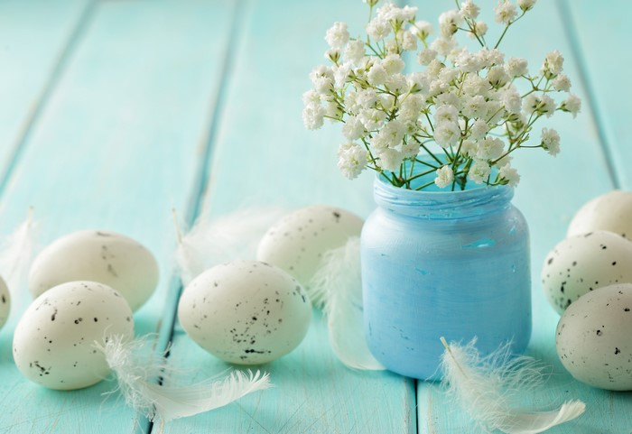 Easter eggs and baby's breath in a blue jar on wood