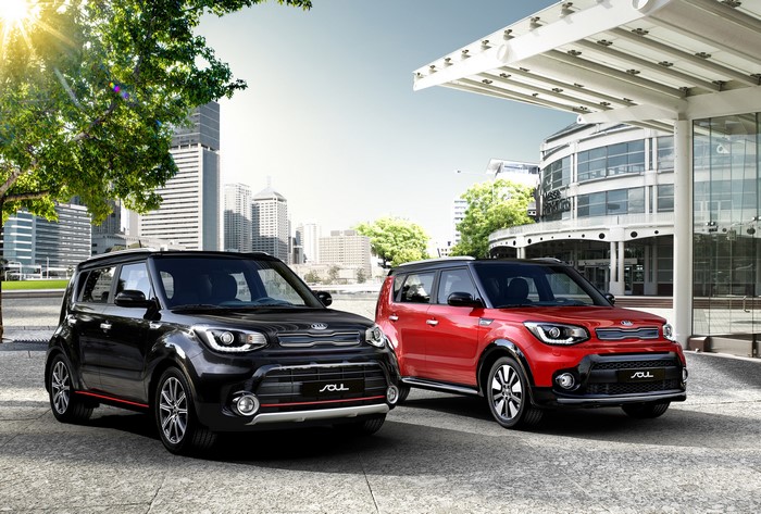 Two Kia Soul cars, black and red, in a city setting