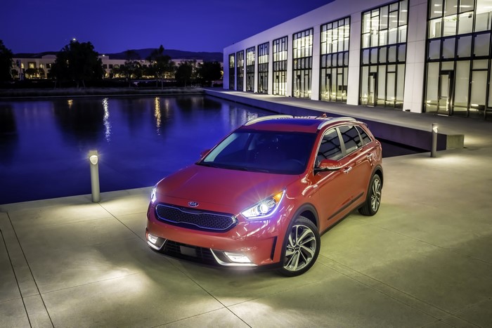 Red Kia Niro Hybrid parked by a modern building at night