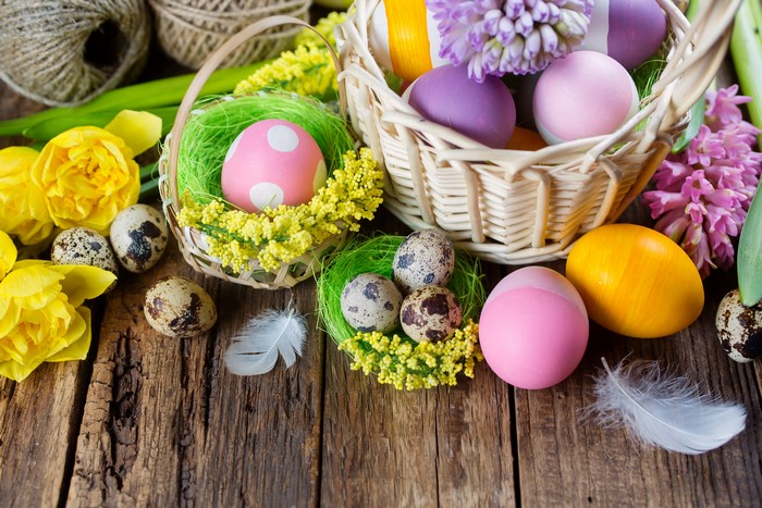 Easter Eggs in Wicker Baskets with Flowers and Feathers