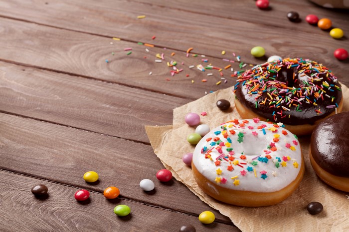 Donuts with chocolate and white icing and sprinkles on wooden planks