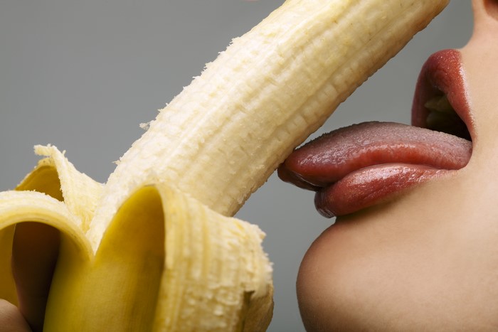 Close-up of a person licking a peeled banana