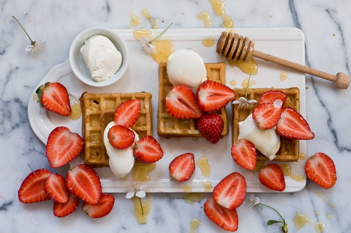 Waffles with strawberries, ice cream, and honey
