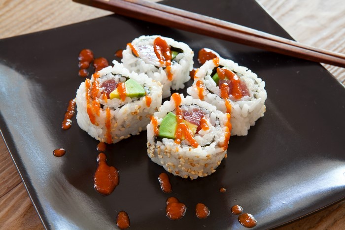 Sushi rolls with avocado and tuna drizzled with sauce