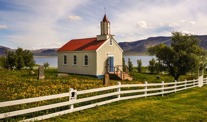 Small white church with red roof in Iceland by a lake
