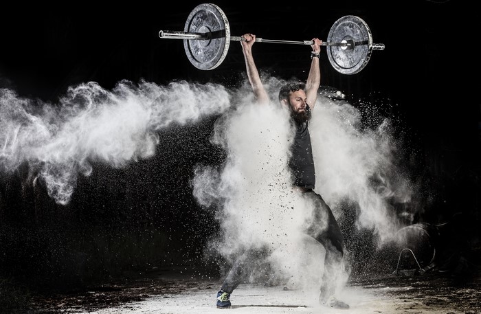 Man lifting barbell with white powder explosion