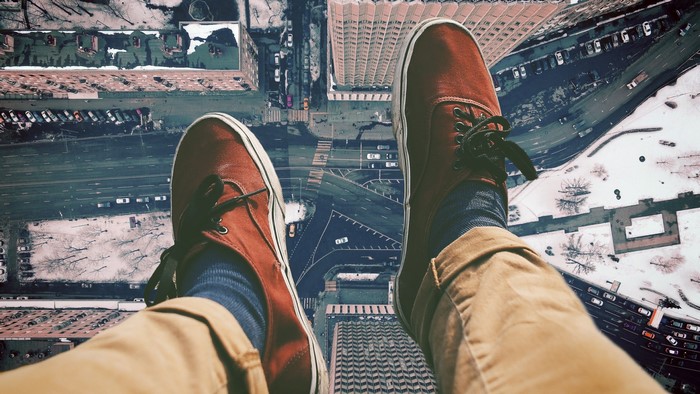 Person's legs and shoes overlooking city street from above