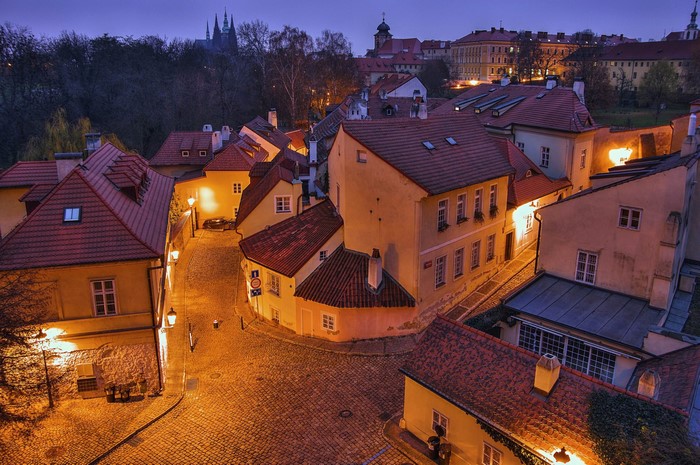 Prague street at dusk with illuminated houses and cobblestones