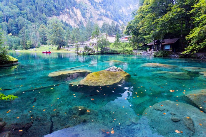 Clear turquoise lake with rocks and trees in Kander Valley, Switzerland