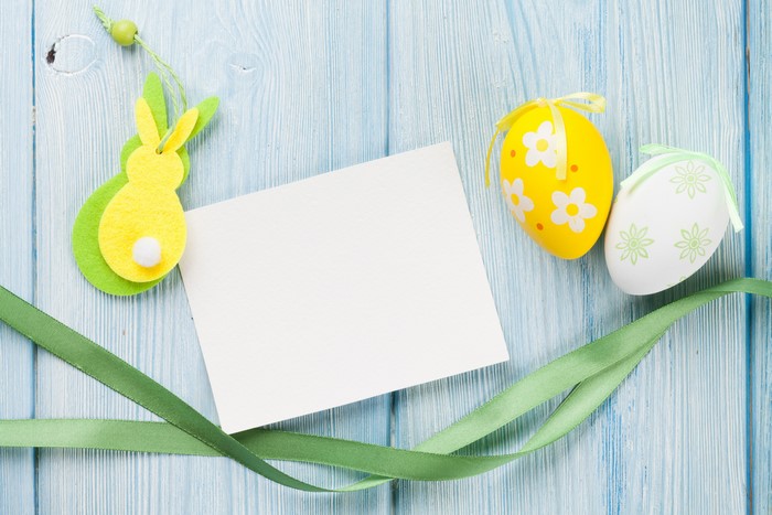 Easter bunny, eggs, ribbon, and card on wood planks