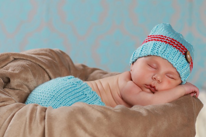 Newborn baby sleeping in a basket wearing a winter hat