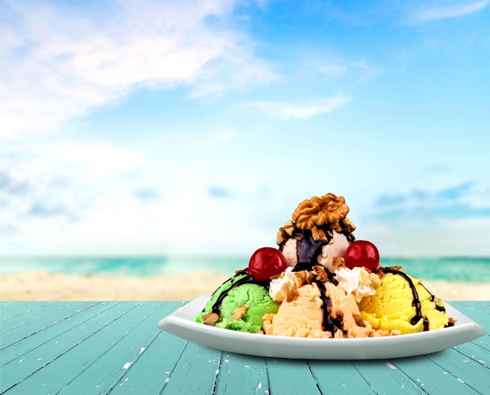 Ice cream sundae with nuts and cherries on a beach background