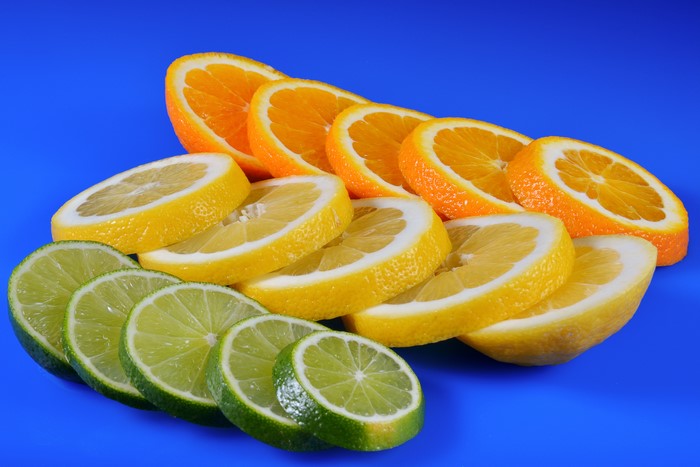 Sliced oranges, lemons, and limes on a blue background