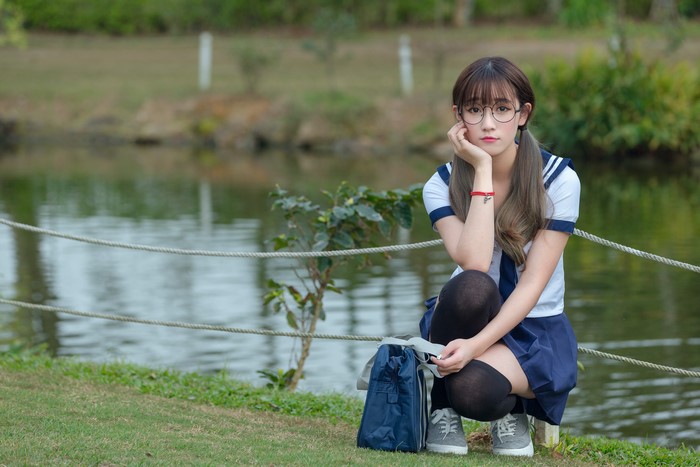 Cute Schoolgirl Sitting by the Lake in Glasses