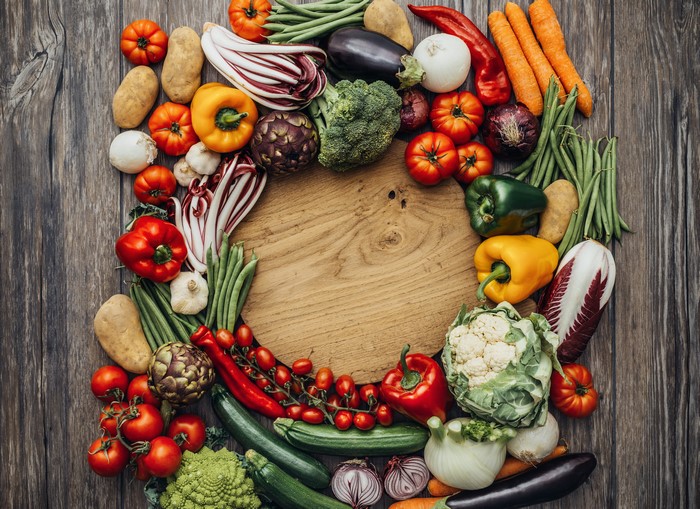 Vegetables arranged around a wooden cutting board