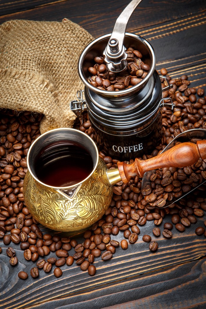 Coffee beans, cezve, and coffee grinder on wooden table