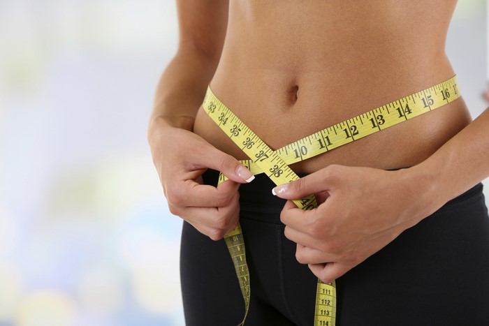 Woman measuring her waist with a tape measure