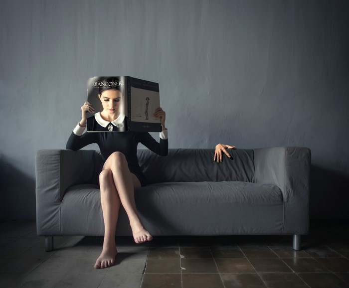 Woman reading magazine on sofa