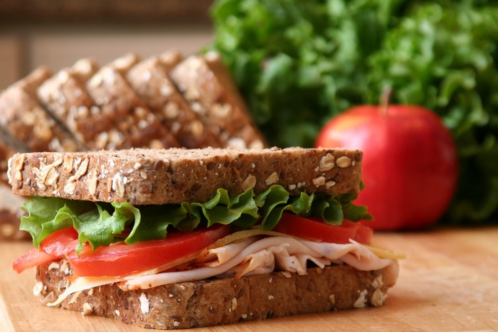 Turkey sandwich with lettuce, tomato, and cheese on whole grain bread