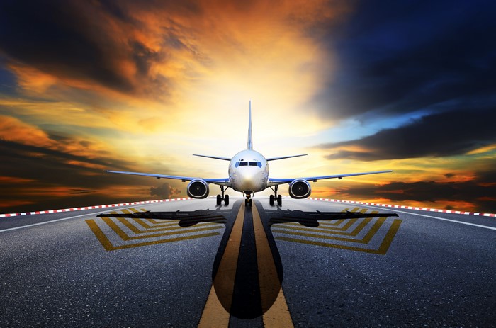 Airplane on runway at sunset