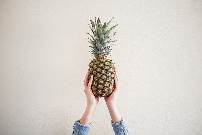 Hands holding a pineapple