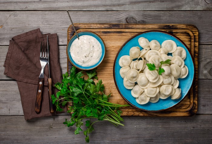 Pelmeni with Dip and Parsley on Wooden Table