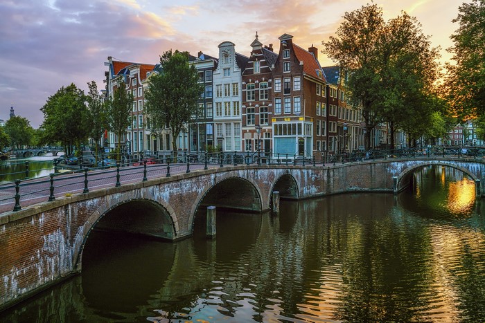 Amsterdam canal with bridges and houses at sunset