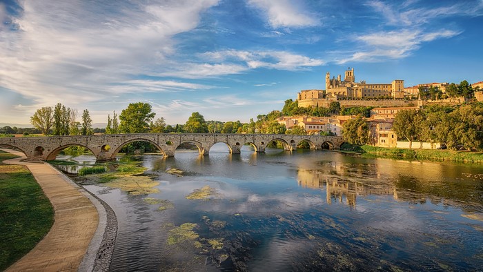 Stone bridge over a river with a town on a hill