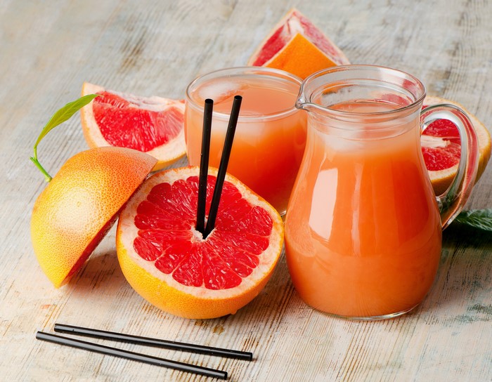 Grapefruit juice in a jug and glass with grapefruits