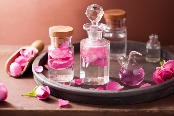 Bottles of rose oil and petals on a tray