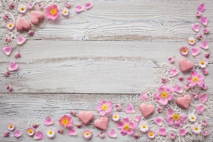 Pink hearts, roses, and daisies on wood planks