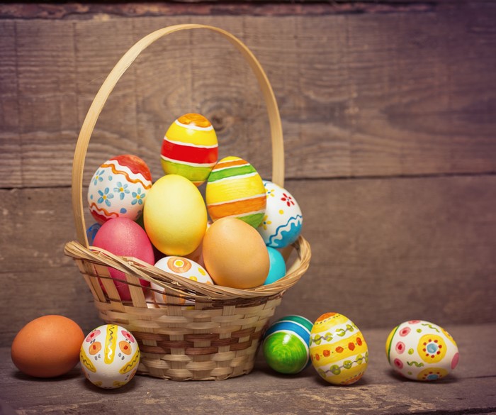 Easter Eggs in Wicker Basket on Wood Planks