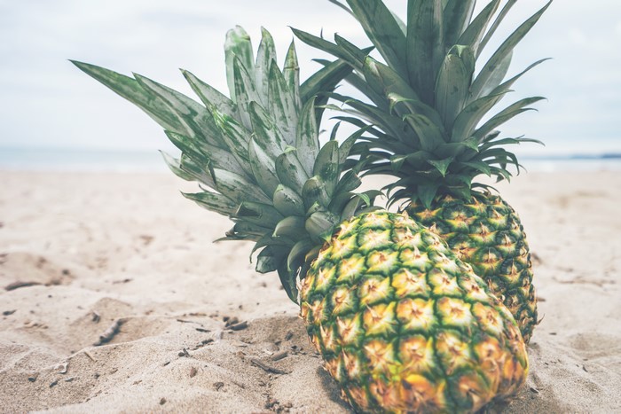 Two pineapples on a sandy beach