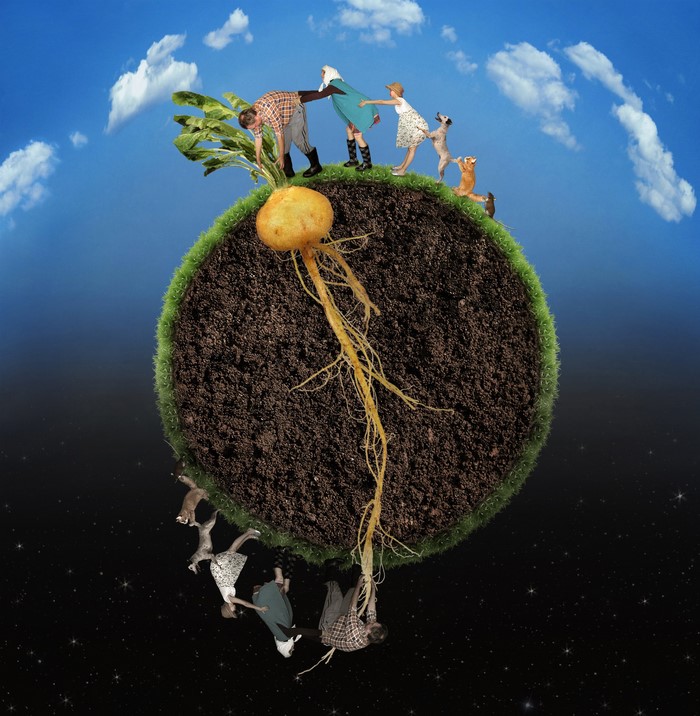 People and animals pulling a giant root vegetable from a planet